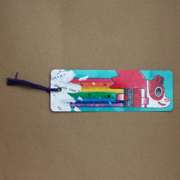 A vibrant bookmark featuring a colorful design, with a tassel, showcasing Super Poppy the guinea pig farting a rainbow.